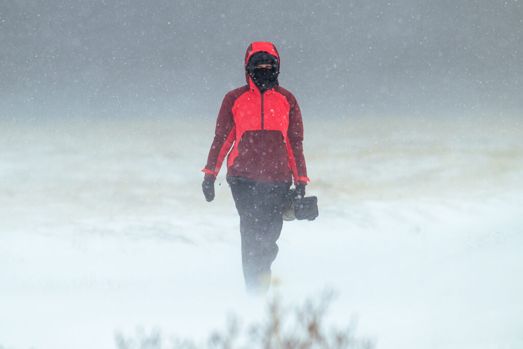 Anne Lindner im Schneesturm auf Island auf der Suche nach Polarfüchsen trägt die Canon R5 mit dem Canon EF 600 IS II F4.0 Objektiv.